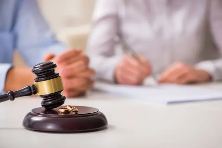 A gavel and two wedding rings are displayed next to a couple filing for divorce.