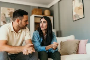 A couple sitting on a couch talks through an agreeable, uncontested divorce.