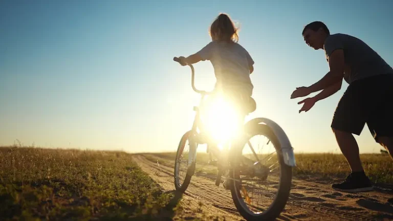 A father teaches his daughter how to ride a bike. This represents a positive family relationship and why you should get legal assistance if you don't pay child support.