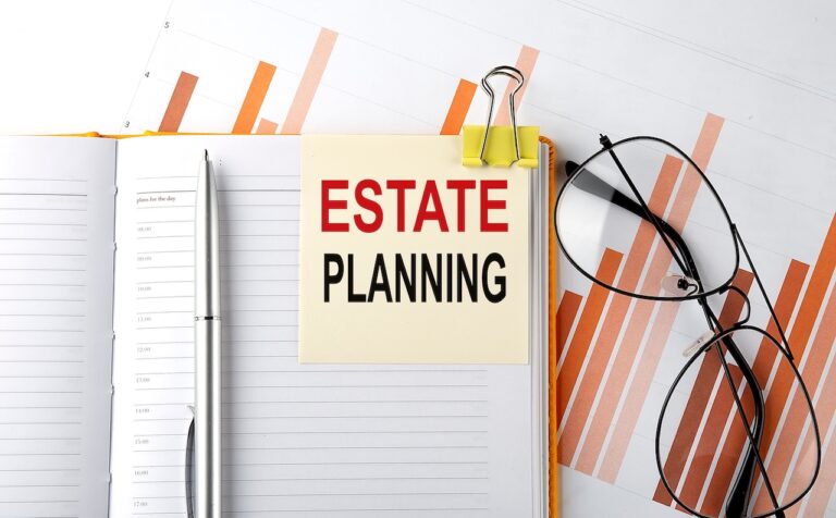 A yellow notecard reading "ESTATE PLANNING" is clipped to a planner with a pen, glasses, and financial charts highlighting common estate planning mistakes to avoid.